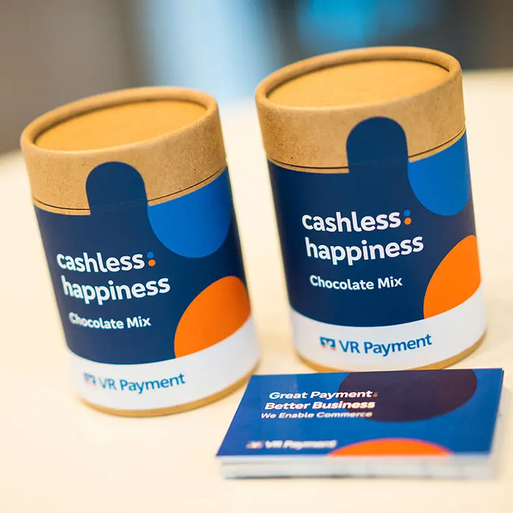 Zwei Verpackungen „cashless happiness – Chocolate Mix“ und ein Flyer von VR Payment auf einem Tisch.