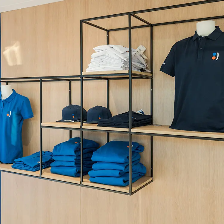 Offenes Regal mit VR Payment-Merchandise: Polohemden, Hoodies, Caps und Shirts ordentlich gefaltet oder ausgestellt.