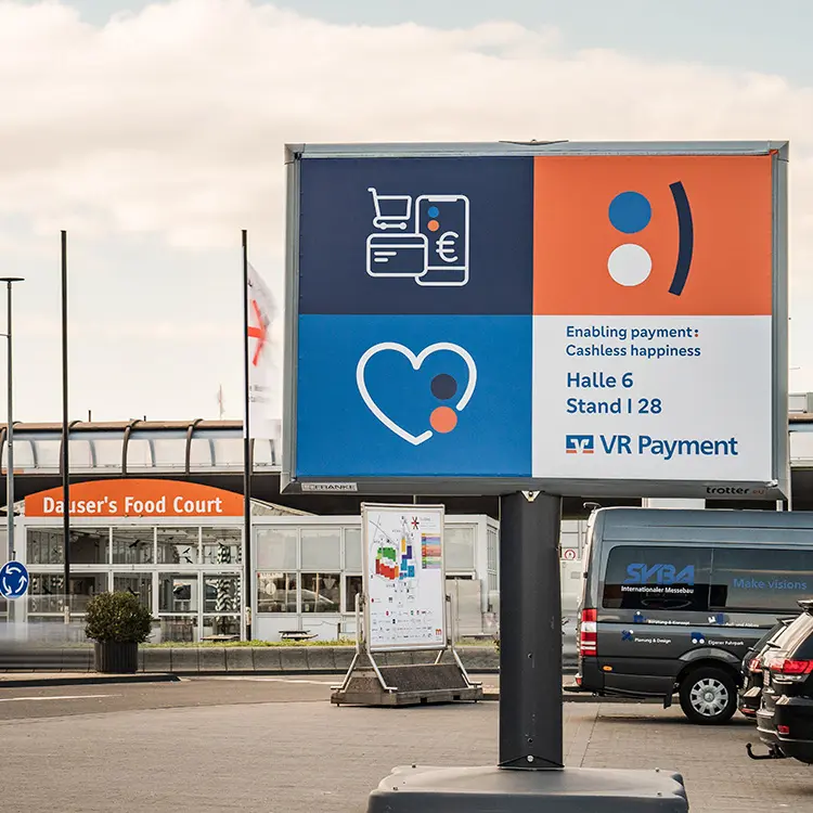Großes Werbeplakat von VR Payment vor Messehalle, mit Infos zum Stand in Halle 6, Stand I 28.