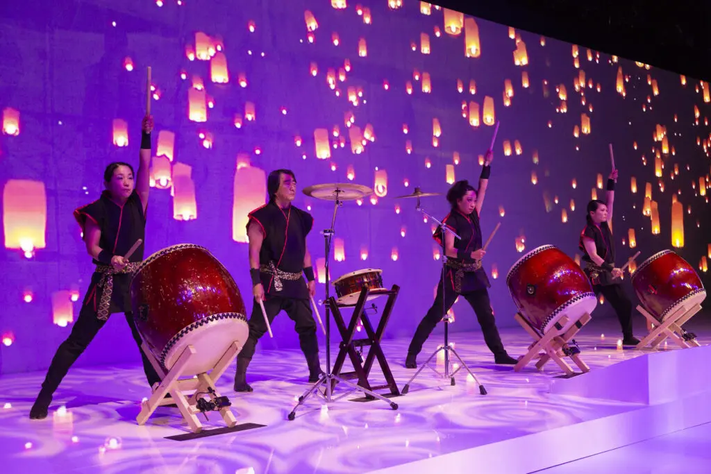 Trommler*innen führen eine dynamische Show mit großen, traditionellen japanischen Taiko-Trommeln auf, begleitet von Laternenprojektion.