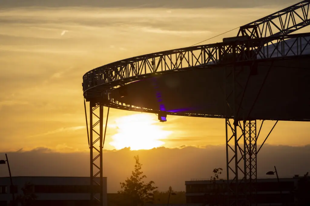 Sonnenuntergang hinter der silbernen Eventdachkonstruktion, deren Metallstreben im warmen Licht leuchten.
