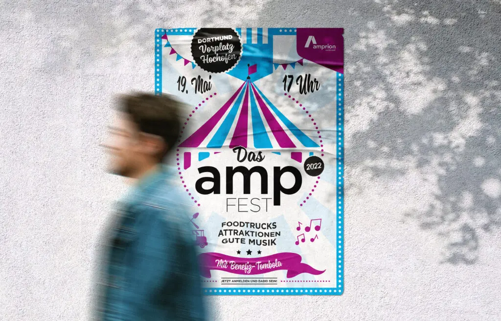 Plakat für das „amp Fest 2022“ mit Zirkuszelt-Grafik in Pink und Blau. Es kündigt das Event am 19. Mai um 17 Uhr in Dortmund (Vorplatz Hochofen) an und wirbt mit Foodtrucks, Attraktionen, guter Musik und einer Benefiz-Tombola. Im Vordergrund läuft eine Person verschwommen vorbei.