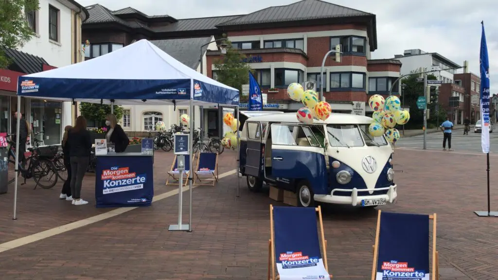 VW Bulli mit Morgen-kann-kommen Volksbanken Raiffeisenbanken Branding und Promotion-Stand mit Liegestühlen und Theke auf einem Marktplatz