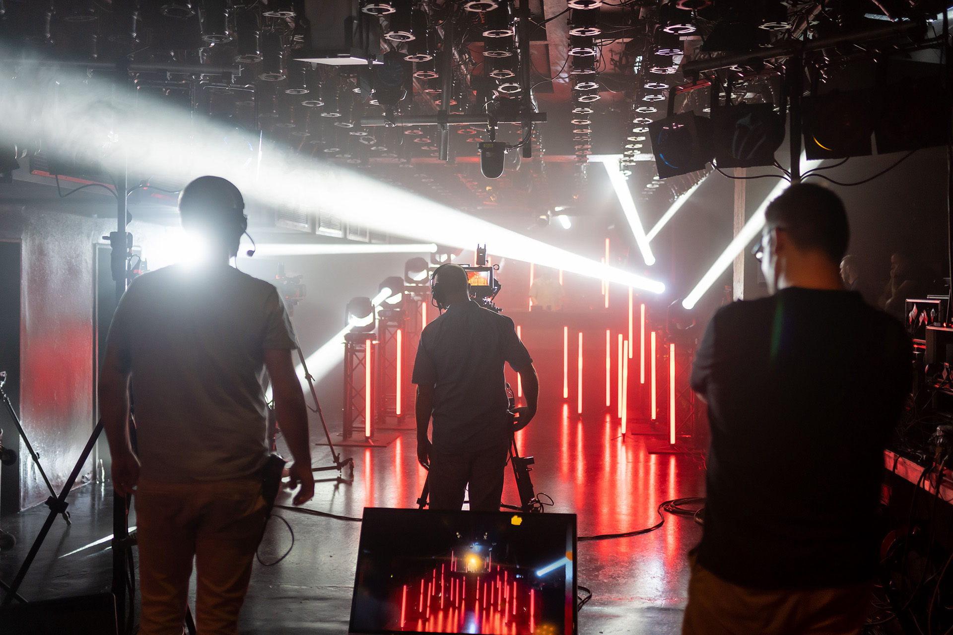 Kamerateam in einer dunklen Eventlocation mit starker Lichtshow und roten LED-Säulen auf der Bühne.