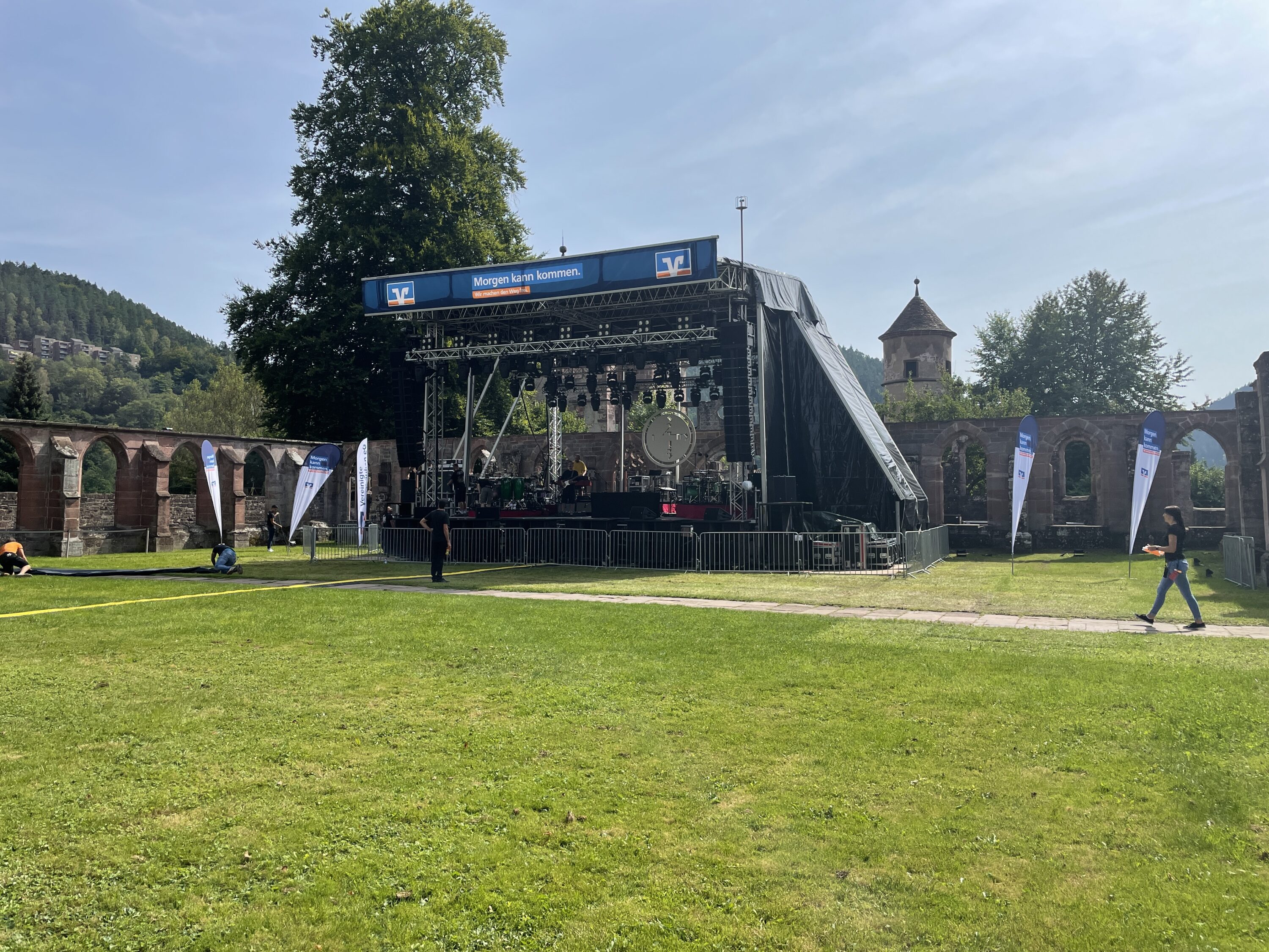 Bühne mit Technikaufbau im Freien vor historischer Kulisse, Banner mit VR-Bank-Logo und dem Schriftzug „Morgen kann kommen.“